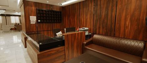 Un espacio de oficina moderno con un mostrador de recepción de madera, asientos de cuero y una mesa de vidrio.