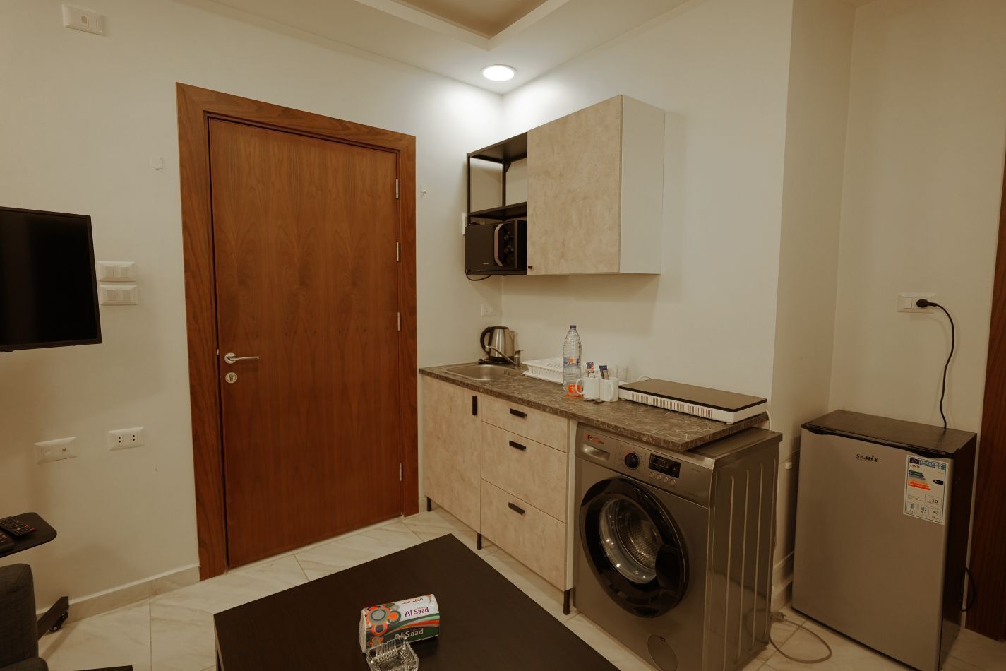 Cocina compacta con lavadora, microondas y refrigerador pequeño.
