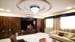 A modern living room with a fireplace, a sofa, a coffee table, and a chandelier. - Nakheel Suites (Irbid)