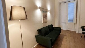 Une pièce avec un canapé vert, un lampadaire et une porte avec une fenêtre.
