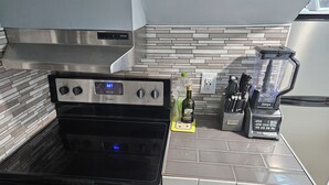 Une cuisine avec un four noir, un four à micro-ondes, un mixeur et un meuble blanc.