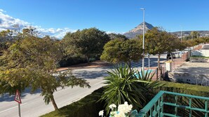 A road with a pedestrian crossing sign, surrounded by greenery and a mountain in the background. - Luxury property in Javea Arenal with garden, roof terrace and shared pool (Xàbia)