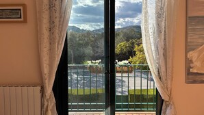 A room with a view of a mountainous landscape through a window with floral curtains. - Luxury property in Javea Arenal with garden, roof terrace and shared pool (Xàbia)