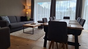 Moderni olohuone, jossa on sohva, sohvapöytä ja ruokapöytä tuoleineen.