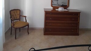 A room with a wooden dresser, a chair, and a mirror.