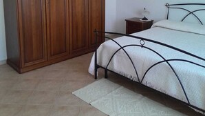 A bedroom with a bed, a wardrobe, a nightstand, and a chandelier.
