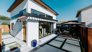 A modern two-story house with a patio area, large windows, and a wooden deck. - 25% off, Chic Casita • Hot tub • BBQ • 4 min to SDSU (La Mesa)
