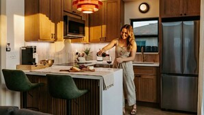A modern kitchen with wooden cabinets, a central island, a stainless steel refrigerator, and a pendant light. - 25% off, Chic Casita • Hot tub • BBQ • 4 min to SDSU (La Mesa)