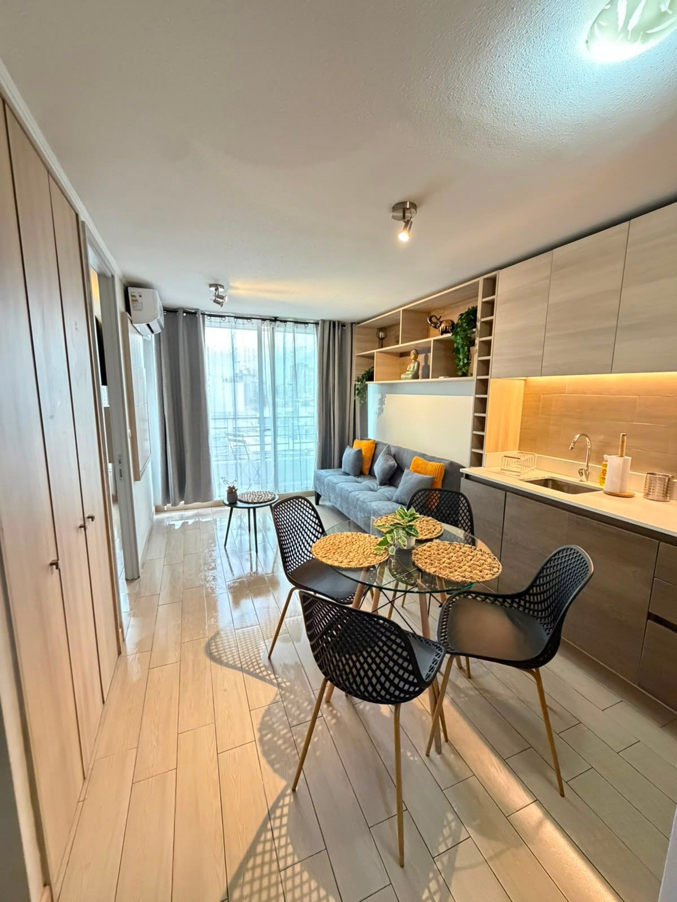 Een modern appartement met een eethoek, kitchenette en een groot raam.