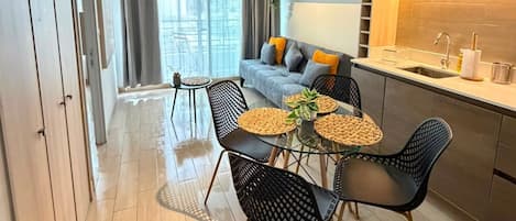 A modern apartment with a dining area, kitchenette, and a large window.