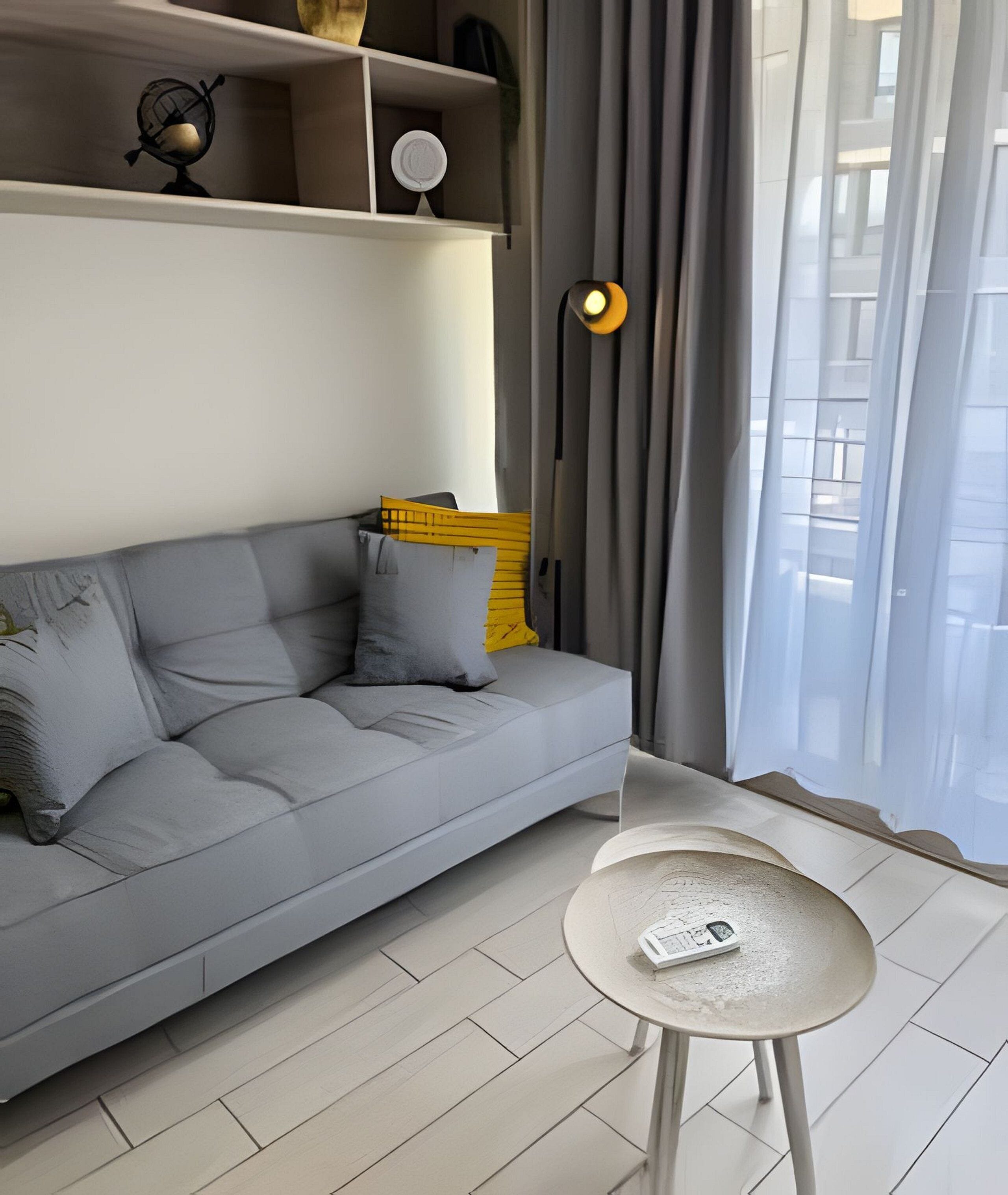 A modern living room with a grey sofa, a small round table, and a lamp.