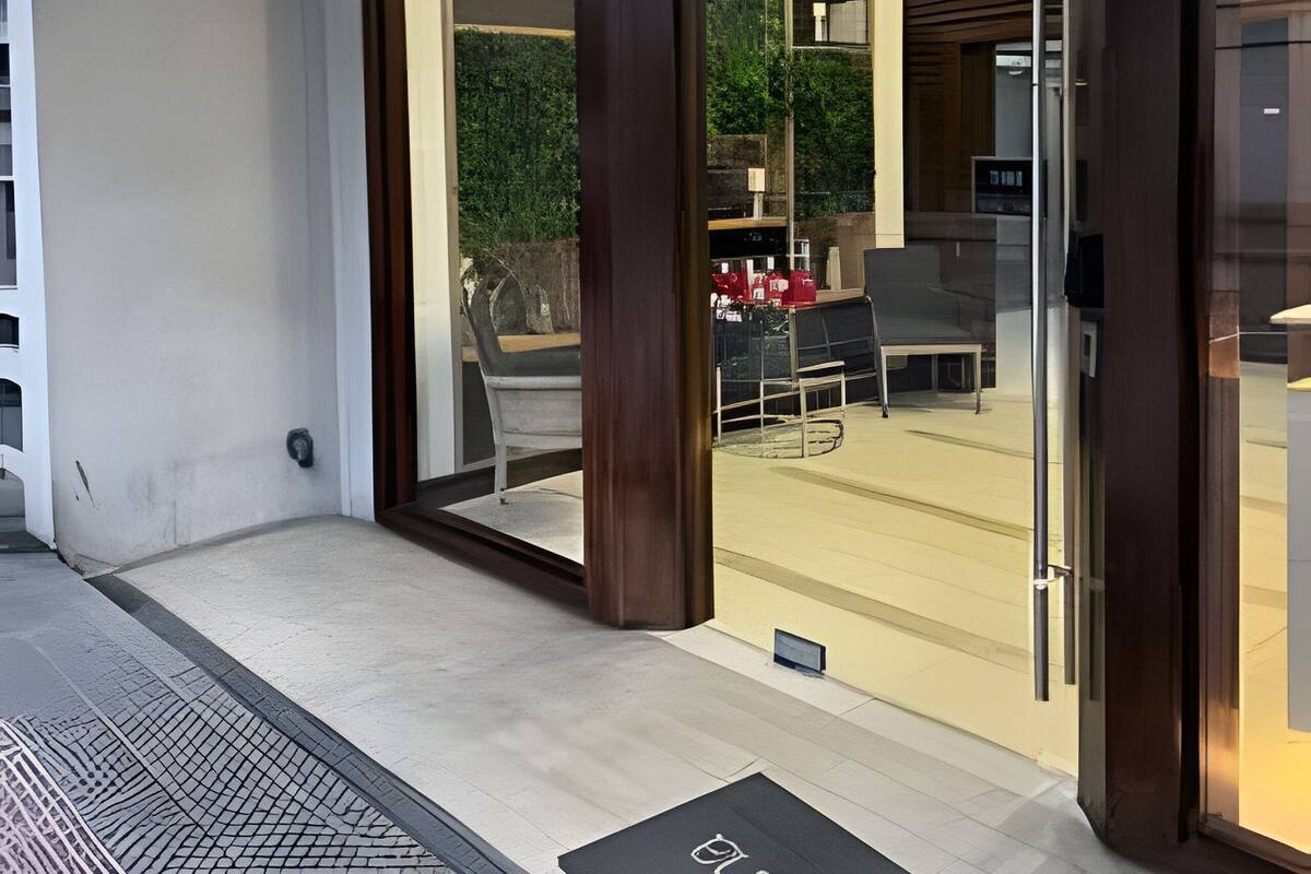 A modern building entrance with a glass door, a number '624' sign, and a doormat with the word 'WELCOME'.