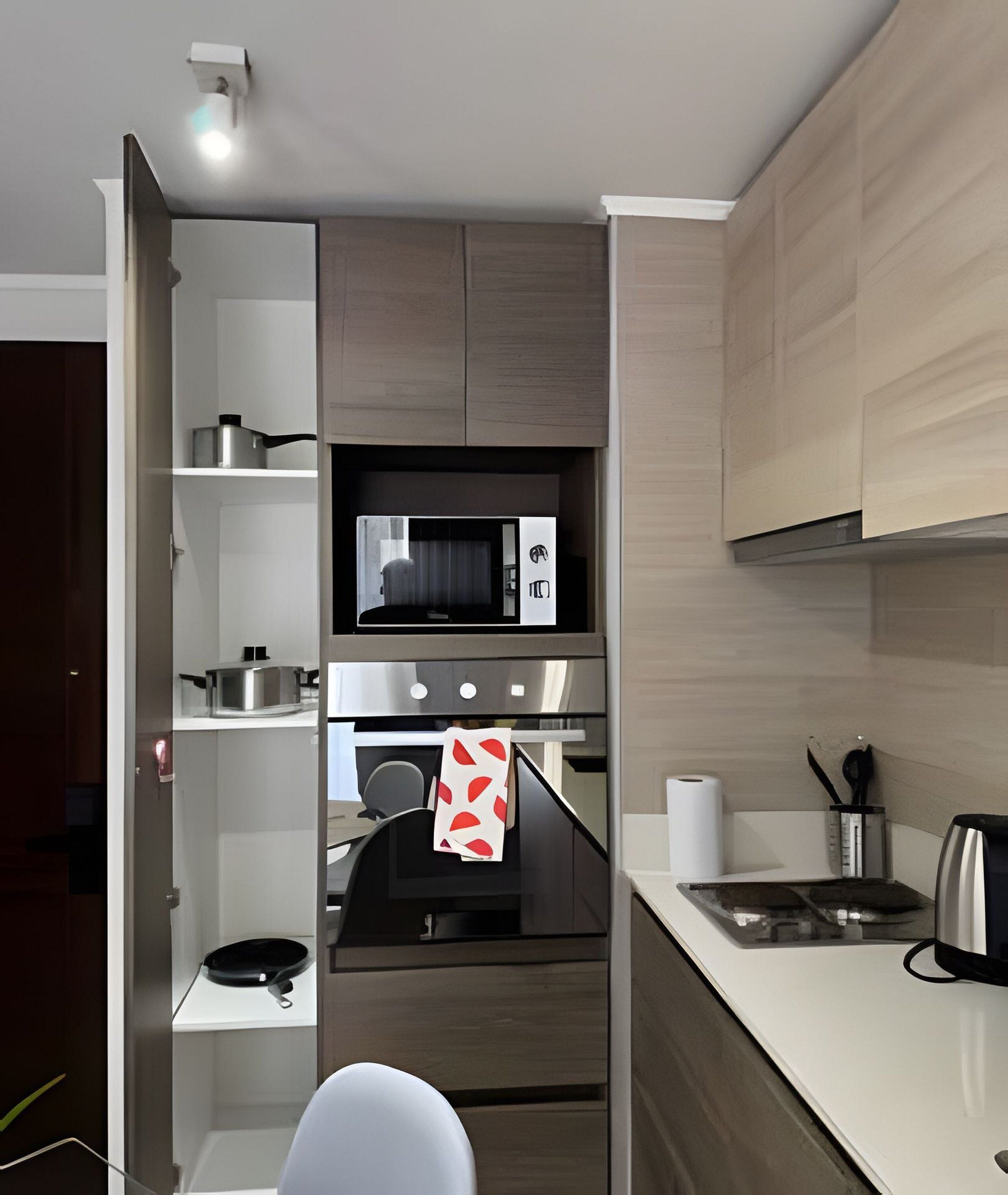 A modern kitchen with built-in appliances, a microwave, oven, and a kettle on the countertop.