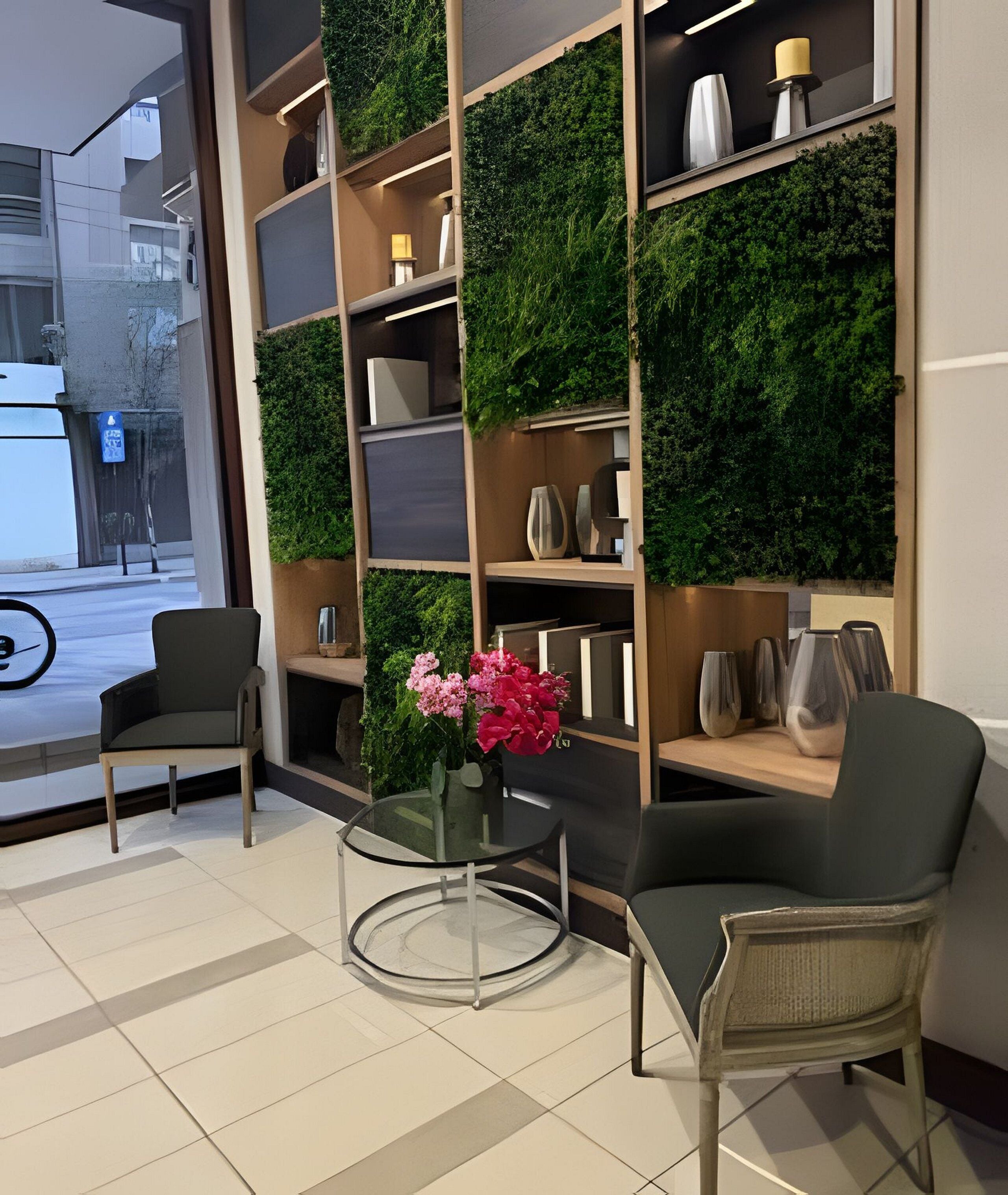 A modern interior with a green wall, two chairs, a small table, and a vase of flowers.