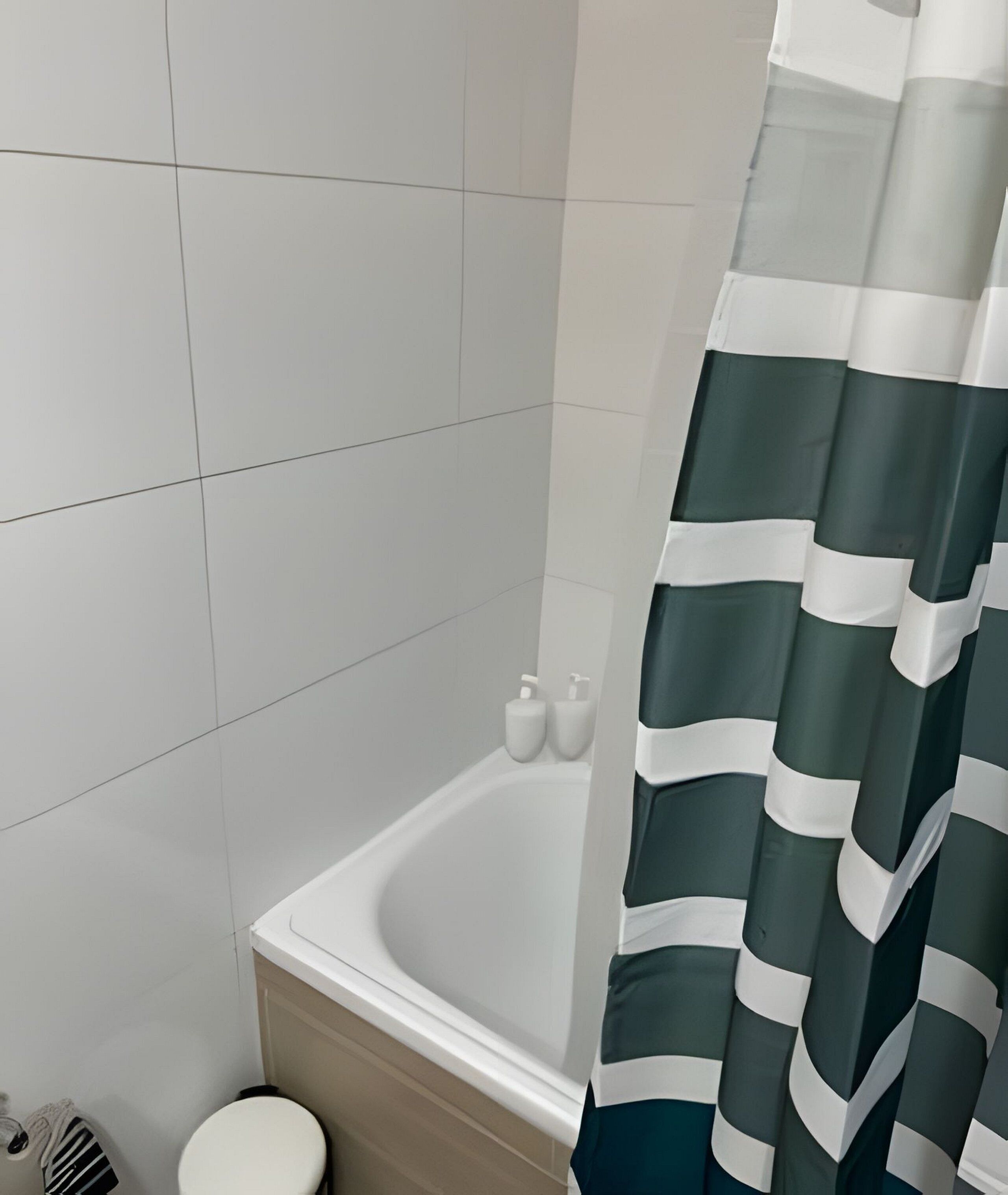 Un baño con una bañera blanca, un inodoro y una cortina de ducha.