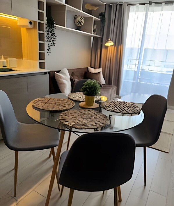 A modern dining area with a glass table, black chairs, and a small potted plant.