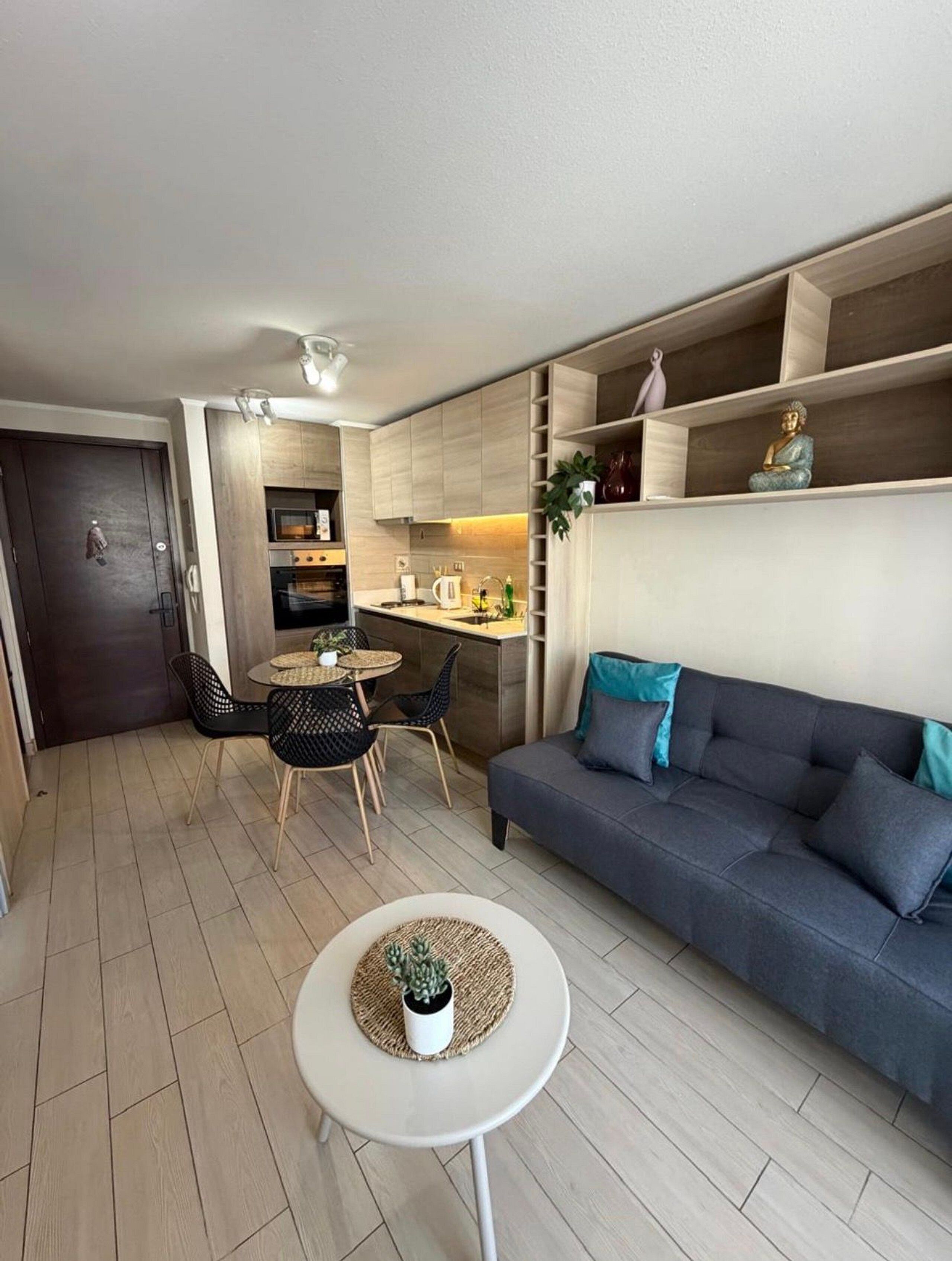 Un espace de vie compact comprenant un coin cuisine, un coin repas et un espace détente avec un canapé et une petite table.