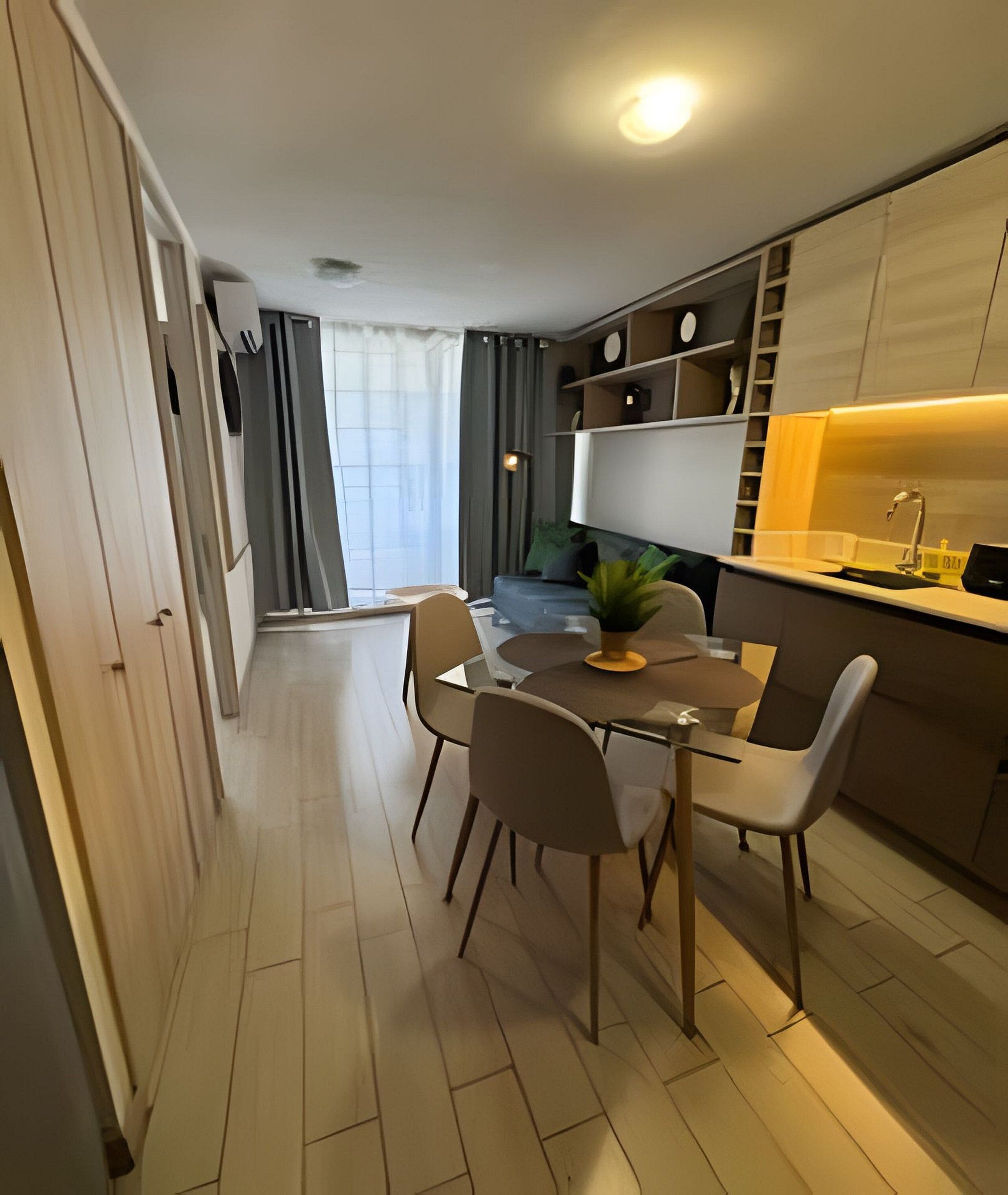 A modern kitchen with a dining area, featuring a central island, chairs, and a small potted plant.