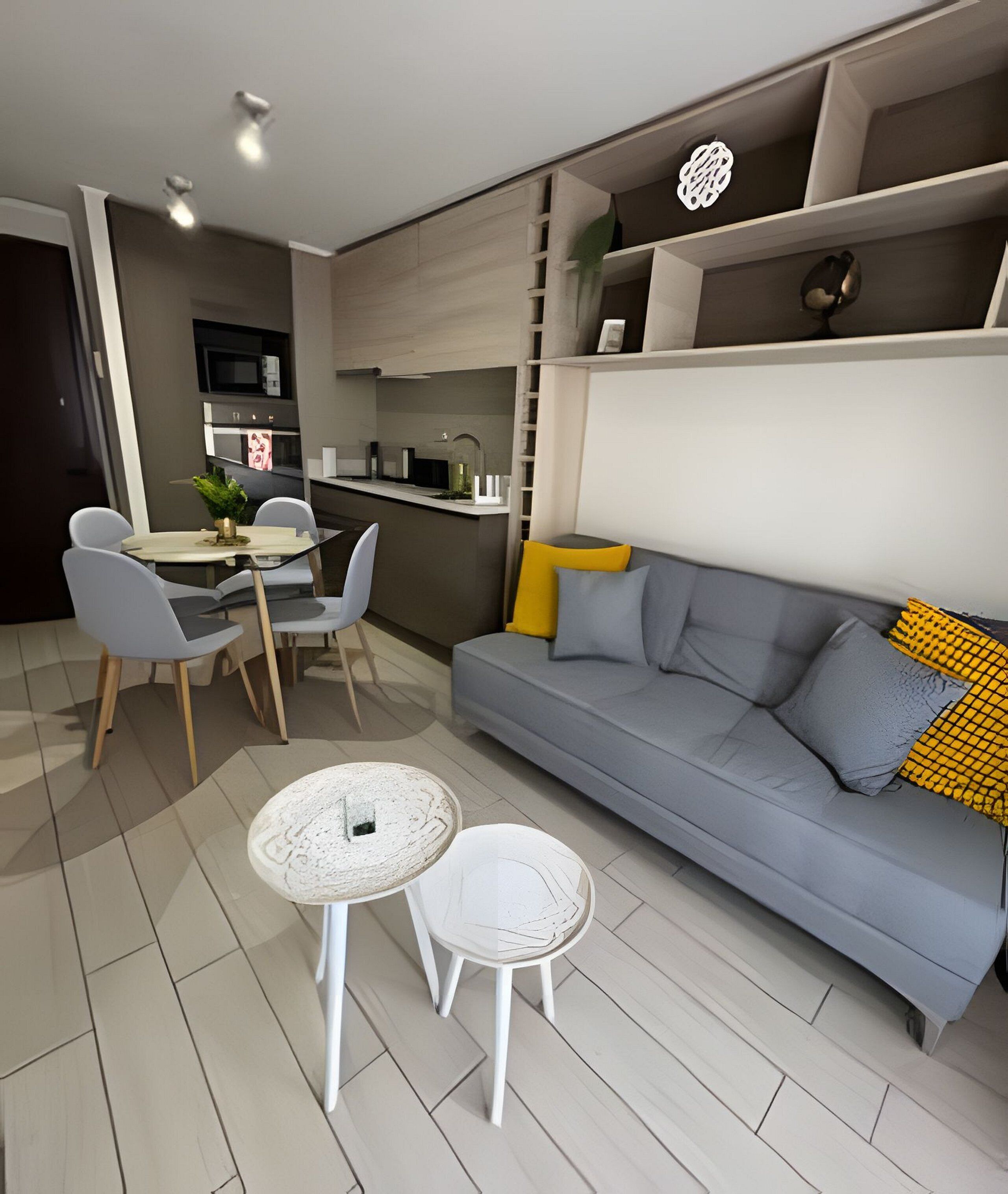 Un salon moderne avec un canapé gris, une petite table blanche et un coin repas avec des chaises.