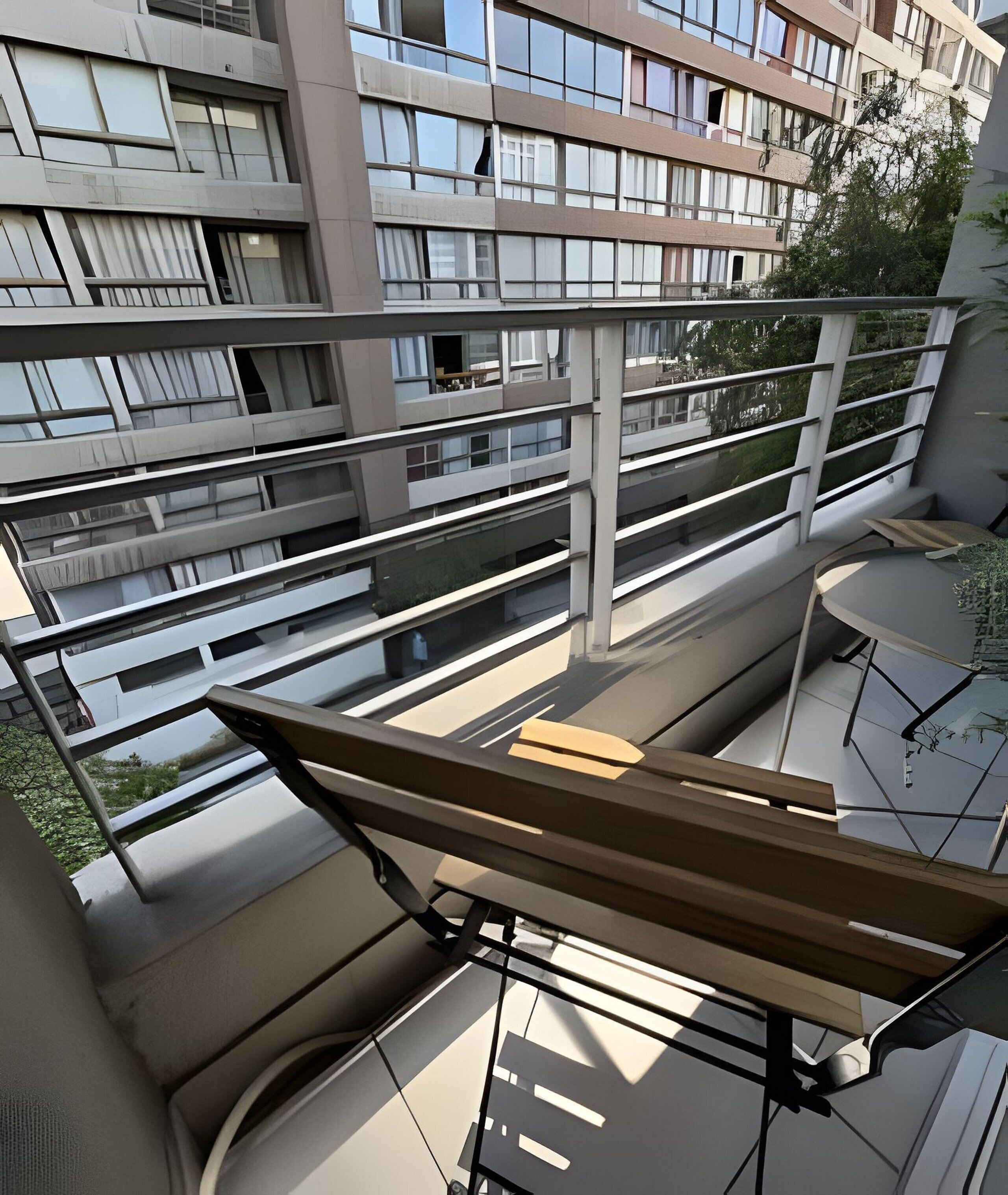 En moderne lejlighed med balkon, store vinduer og udsigt til andre bygninger.