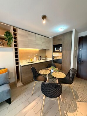 A modern kitchen with a dining area, built-in cabinets, and a small dining table with chairs. - collection R 1 (Santiago)
