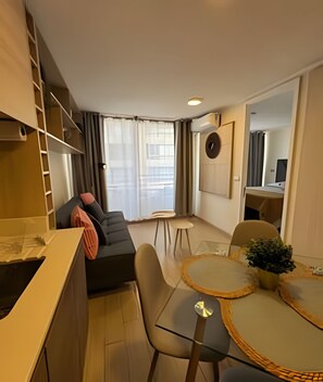 A compact living space with a sofa, a dining table, and a small kitchen area.
