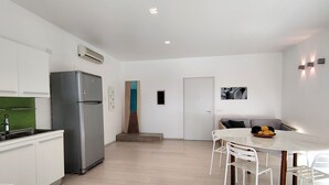 Een moderne keuken met een inbouwkoelkast, een eethoek met een tafel en stoelen, en een kleine trap die naar een andere kamer leidt.