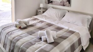 Een slaapkamer met een bed, kussens, een nachtkastje, een plafondventilator en een groot schilderij aan de muur.