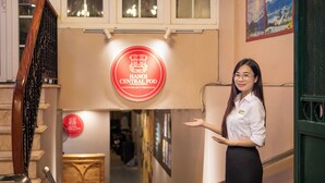 A woman standing in a hallway with a sign reading "HANOI CENTRAL POD" above a staircase. - Hanoi Central Pod (Hanoi)