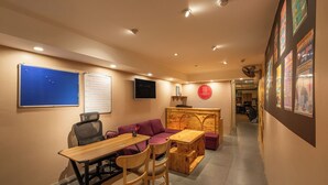 A room with a wooden table, purple sofa, and a TV mounted on the wall. - Hanoi Central Pod (Hanoi)