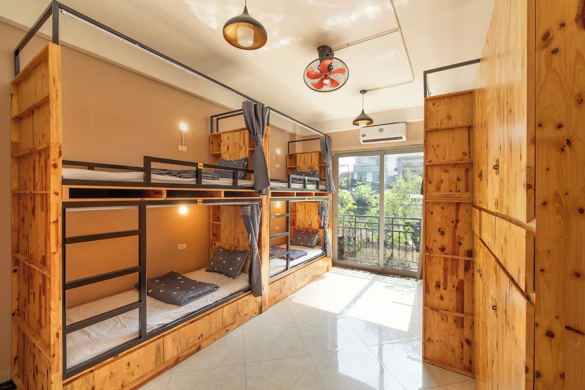 A room with bunk beds, a fan, and a view of the outdoors.