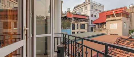 Un balcón con puerta de vidrio, un cubo de basura y vistas a edificios vecinos.