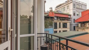 A balcony with a glass door, a trash bin, and a metal railing. - Hanoi Central Pod (Hanoi)