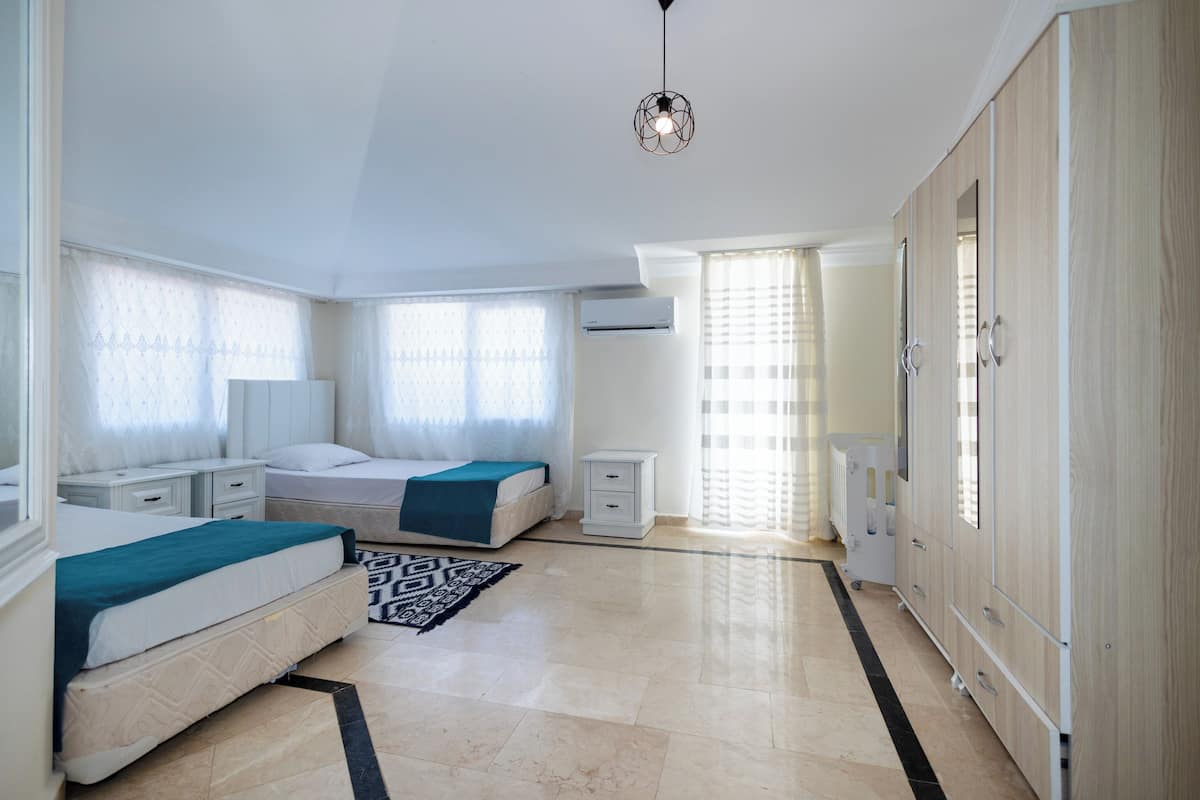 A bedroom with a bed, bedside tables, a nightstand, a dresser, and a radiator.