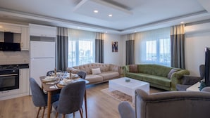 A modern living room with a dining area, a green sofa, and a flat-screen TV. - Konakhan Residence (Alanya)