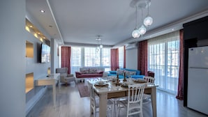 A modern living space with a dining area, sofa, and kitchen. - Konakhan Residence (Alanya)
