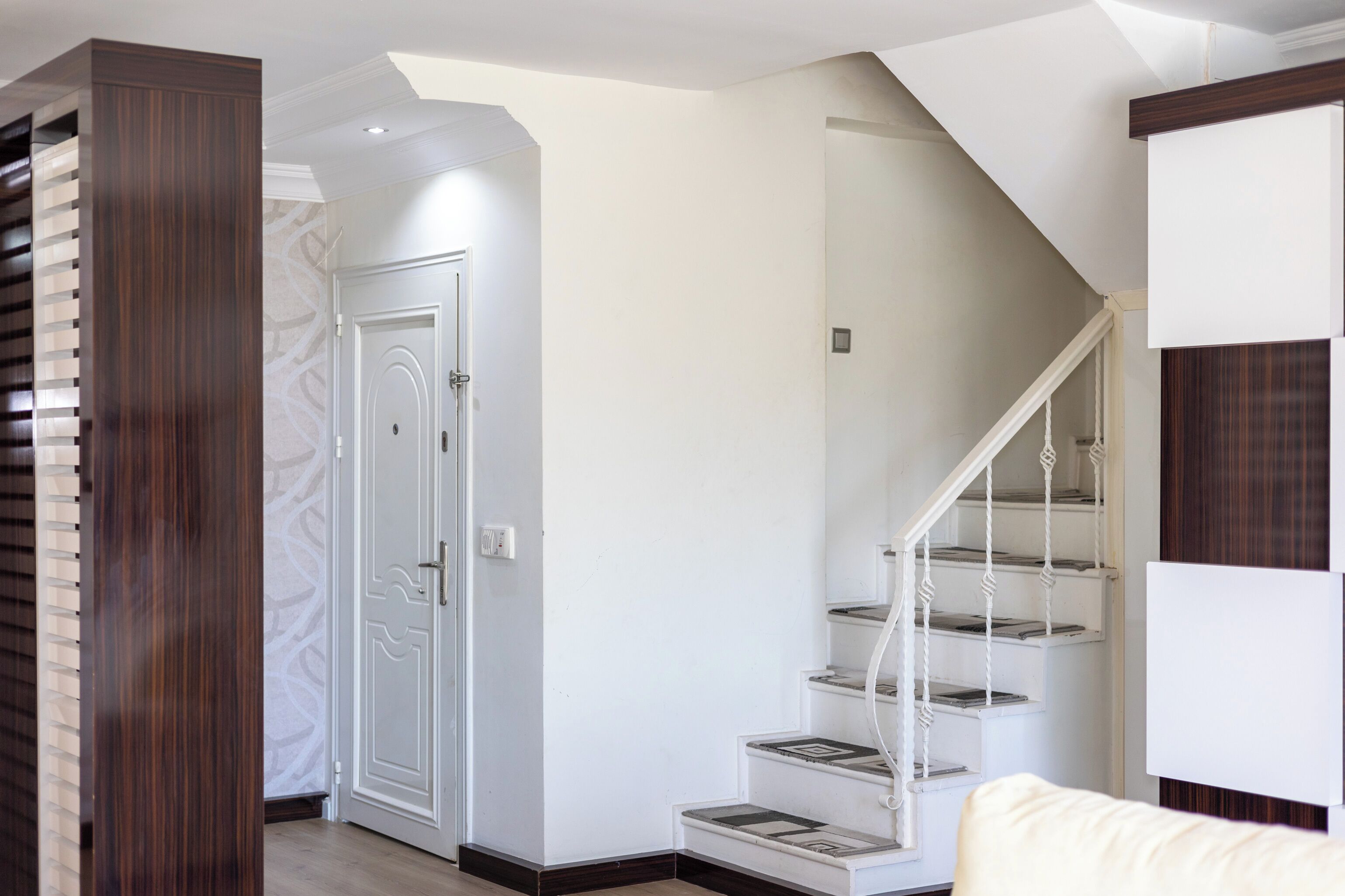 Una escalera con barandillas blancas y un pilar de madera a la izquierda.