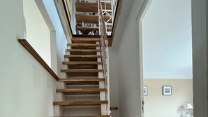 Un escalier en bois menant à un palier où se trouve une bibliothèque.