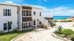 Une maison moderne à deux étages, dotée d’une façade en pierre, d’une couleur blanche et d’un balcon avec une balustrade blanche.