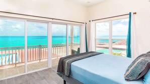 Une chambre dotée d’une grande porte-fenêtre coulissante donnant sur un balcon avec vue sur l’océan.