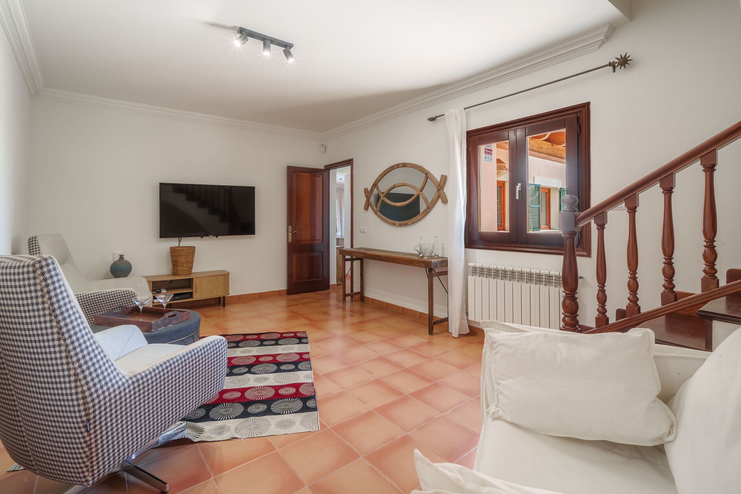 Un soggiorno con un divano, una TV, un tavolo in legno e una scala.