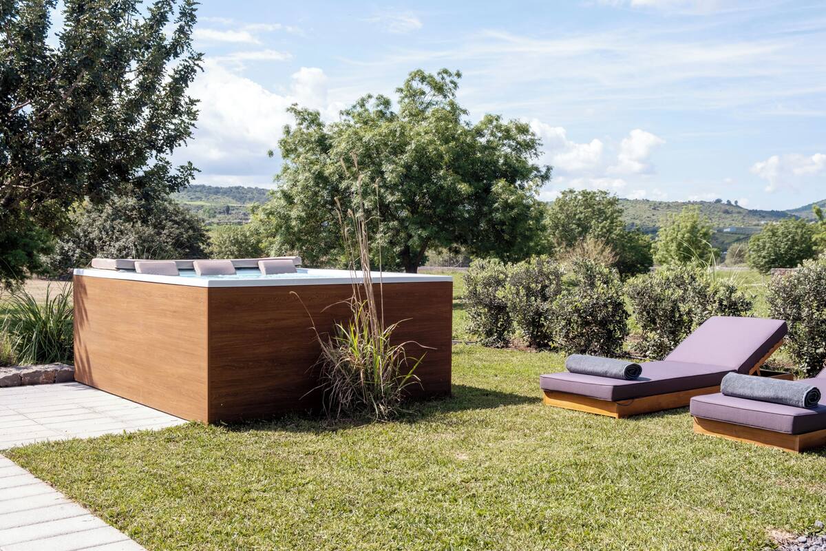 Un espacio exterior moderno con mobiliario de madera y dos sillones reclinables.