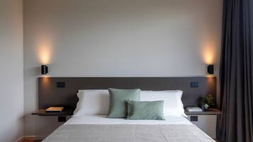 A neatly arranged bedroom with a large bed, two bedside tables, and wall-mounted lighting.