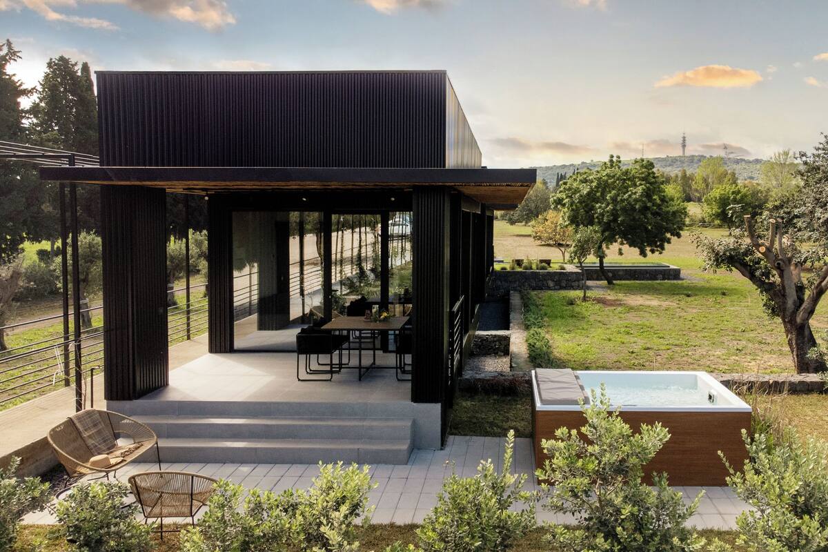 Una casa moderna con un patio, mobiliario exterior y un jacuzzi.