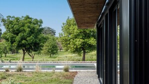 A modern building with a wooden roof, large windows, and a view of a green landscape with trees and a water feature. - Scorzamara Exclusive Country Lodges - Private Pool or Jacuzzi (Melilli)