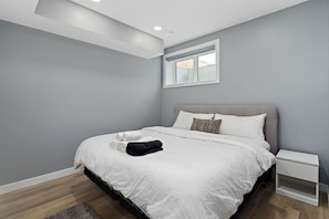 A bedroom with a bed, a nightstand, a window, and a ceiling light.
