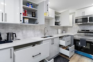 A modern kitchen with white cabinets, stainless steel appliances, and a built-in oven.