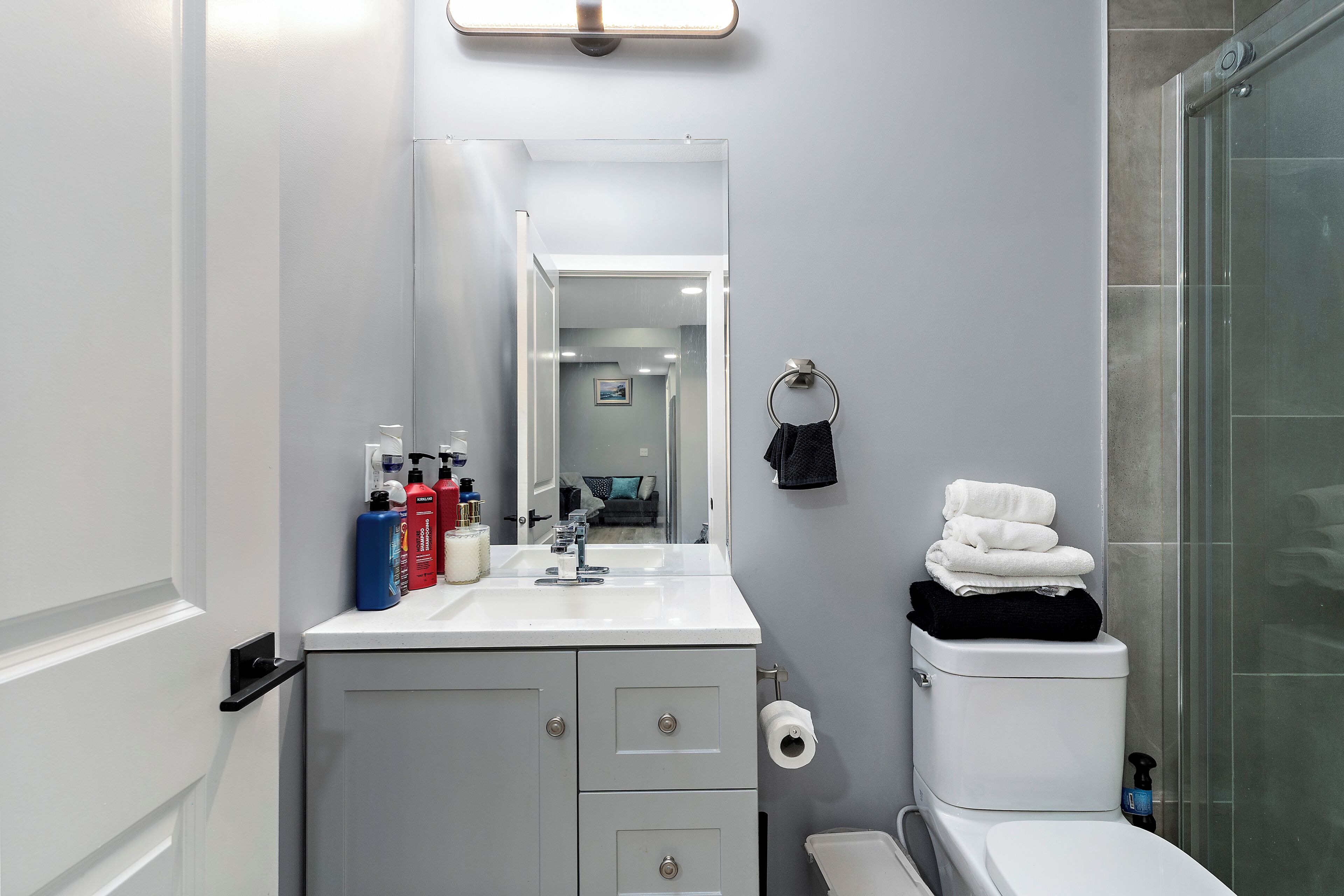 A bathroom with a white sink, mirror, toilet, and glass shower enclosure.