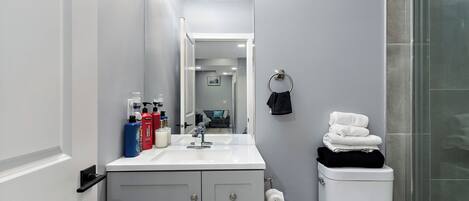 A bathroom with a white sink, mirror, toilet, and glass shower enclosure.