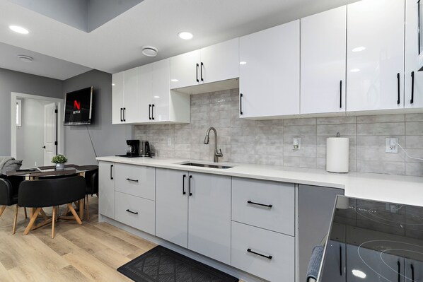 A modern kitchen with white cabinets, a built-in oven, and a sink.